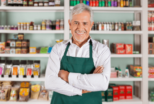 Smiling grocer in front of the shelves